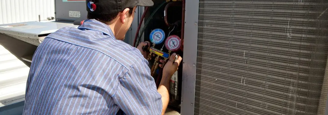 HVAC technician servicing a condenser unit in Worthington